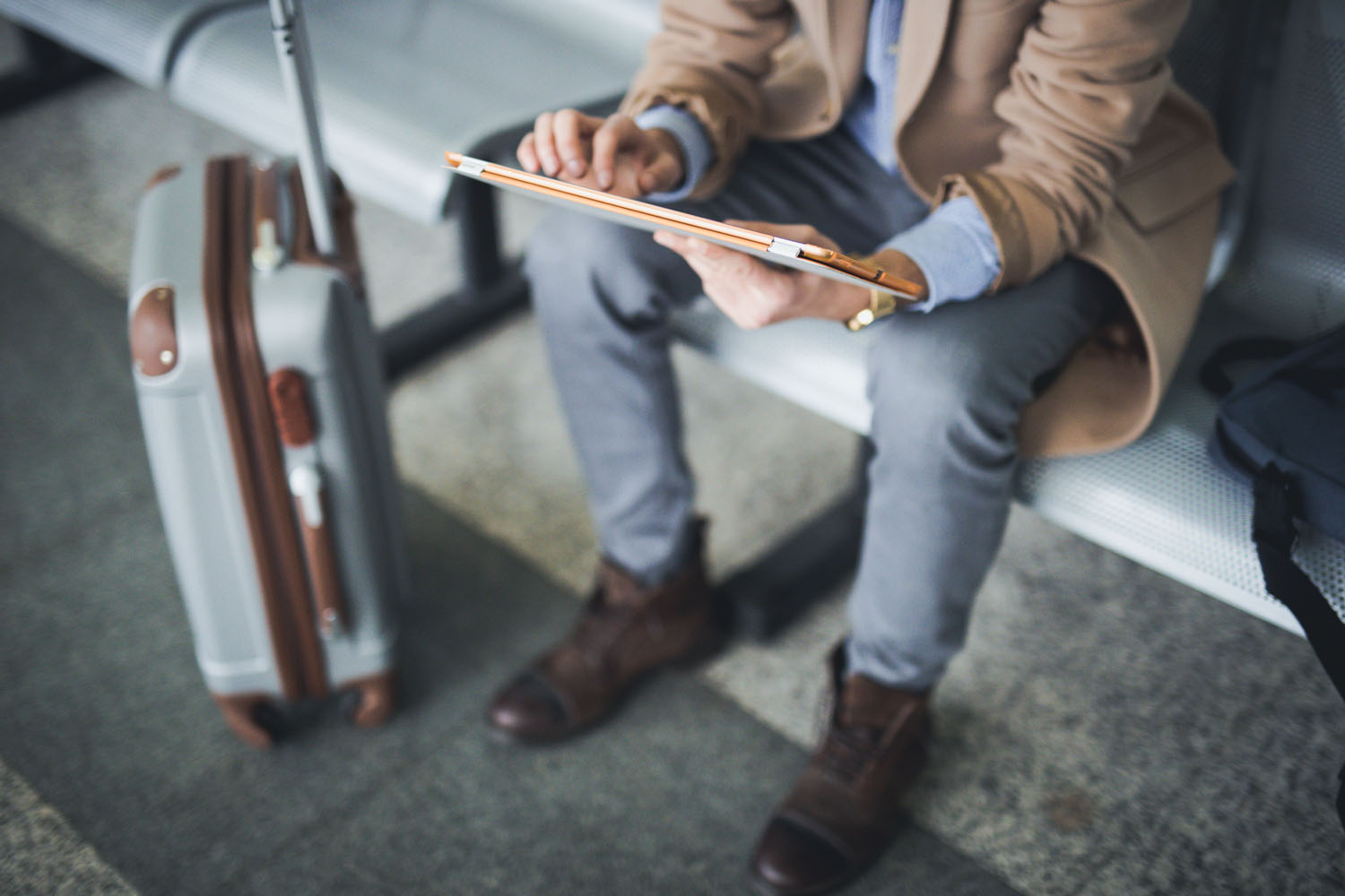 Man uses tablet in airport lounge.