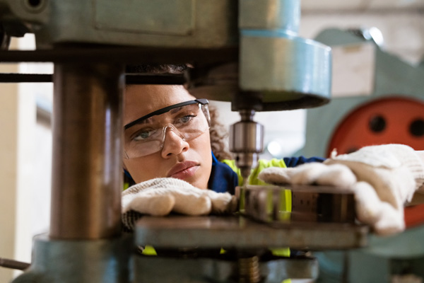 Skilled employee uses heavy machinery at factory.