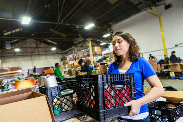 Volunteer helps organize donations at food bank.